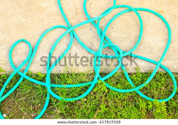 Rubber band water plastic hose on stay on the\
lawn and cement.\
\
