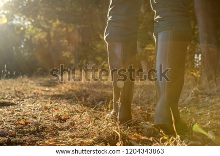 Rubber boots in backlight.. Hunter goes through his hunting grounds with rubber boots towards the setting sun.
