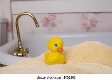 Rubber Ducky Resting On A Towel By Bathtub