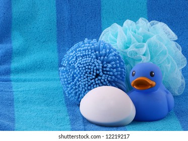 Rubber Ducky, Soap, Sponge And Poof On A Striped Beach Towel