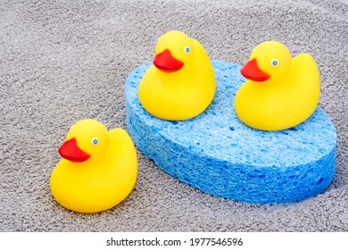 Rubber Ducky Toys And Blue Bath Sponge Isolated On Towel