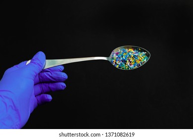 Rubber Gloved Hand Holding A Spoon With Microplastic On Black Background Microplastic Problem. Threat To Human Health And The Environment. Dangerous Additives. Toxic Substances.