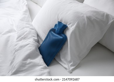 Rubber Hot Water Bottle Near Soft Pillow On Bed