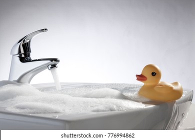 Rubber (plastic) Duck Taking A Bubble Bath In The Sink.