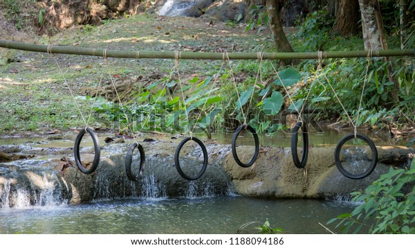 The rubber ring is tied on the log above the\
water surface. Unused motorcycle tires are tied up on the wood over\
water at rural Thailand.