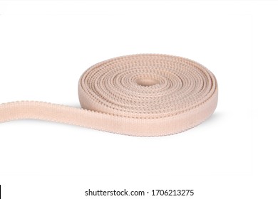 Rubber Roll. Beige Elastic Band Roll For Sewing Close-up. Fabric Tape For Needlework Of The Cloth On White Background. Cloth Ribbon Made Of Polyester Fibre For The Production Of Knitwear Textile Tapes