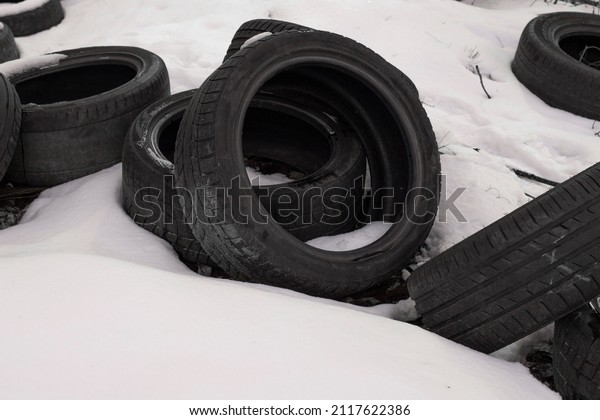 Rubber tires in the snow. Winter tires. Pile of\
old tires. Tire warehouse on the street in the snow. Unnecessary\
rubber tires.