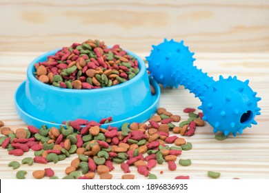 Rubber toy and dry food for pet on wooden background