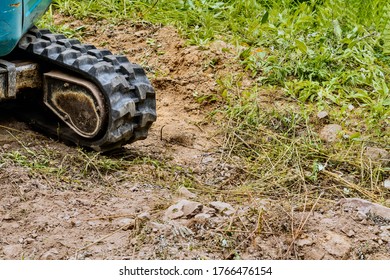 Rubber Tracks On Small Backhoe Parked In Clearing In Recreational Forest Park.