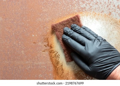 Rubbing rust off sheet steel with an abrasive pad.  Restoration project concept - Shutterstock ID 2198767699