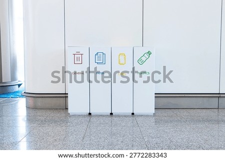 Rubbish bin garbage square shape geometry white plastic with icon general, paper, can, text read on airport ground on wall is background.  Waste collection equipment in park. Protect environment.