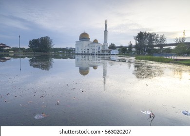 Rubbish Pollution With Plastic And Other Packaging Stuffs On The Lake With Mosque Background. Enviromental Concept.