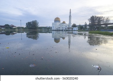 Rubbish Pollution With Plastic And Other Packaging Stuffs On The Lake With Mosque Background. Enviromental Concept.