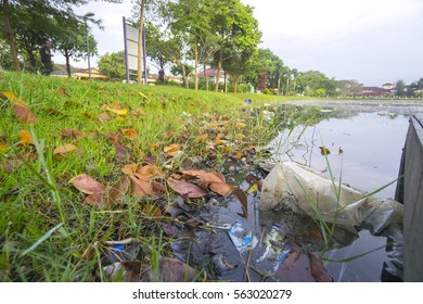 Rubbish Pollution With Plastic And Other Packaging Stuffs On The Lake With Mosque Background. Enviromental Concept.