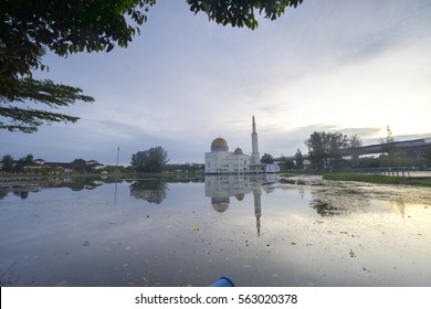 Rubbish Pollution With Plastic And Other Packaging Stuffs On The Lake With Mosque Background. Enviromental Concept.