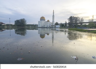 Rubbish Pollution With Plastic And Other Packaging Stuffs On The Lake With Mosque Background. Enviromental Concept.