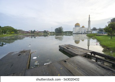 Rubbish Pollution With Plastic And Other Packaging Stuffs On The Lake With Mosque Background. Enviromental Concept.