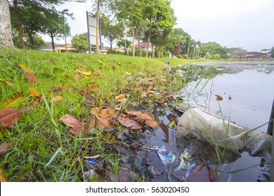 Rubbish Pollution With Plastic And Other Packaging Stuffs On The Lake With Mosque Background. Enviromental Concept.