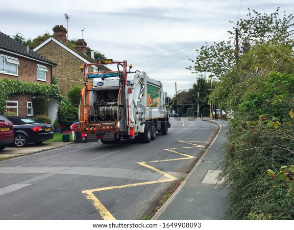 Rubbish truck back\
view. Garbage collection near houses in a suburb of London. London,\
England - March, 2019.