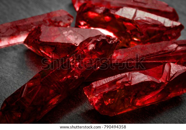 Rubies and raw crystal gems concept\
with closeup of a bunch of red rough uncut ruby\
crystals