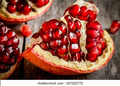 ruby juicy pomegranate grains closeup on a rustic wooden table
