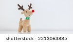 Rudolph the Red-nosed Reindeer soft toy smiling on white snowy background, waiting for Christmas, copy space on the right