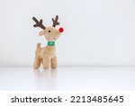 Rudolph the Red-nosed Reindeer soft toy isolated on white snowy background, Christmas concept, copy space on right