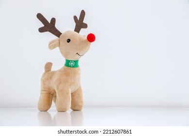 Rudolph the Red-nosed Reindeer soft toy smiling on white snowy background, Christmas concept