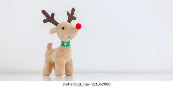 Rudolph the Red-nosed Reindeer soft toy smiling on white snowy background, waiting for Christmas, copy space on the right