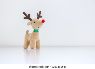 Rudolph the Red-nosed Reindeer soft toy isolated on white snowy background, Christmas concept, copy space on right