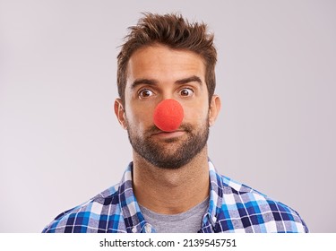 Rudolph Is Unavailable So Ill Be Guiding Your Sleigh. Studio Shot Of A Handsome Man Wearing A Red Nose Against A Gray Background.