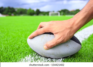 Rugby Ball In Hand On Green Grass 