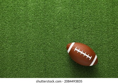 Rugby ball on green grass, top view