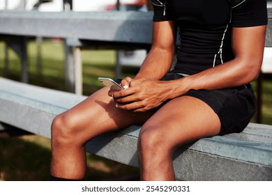 Rugby, hands and man with phone for game results, competition and texting on bench to relax at field. Fitness, athlete and player on mobile app for sports, social media and check score on internet - Powered by Shutterstock