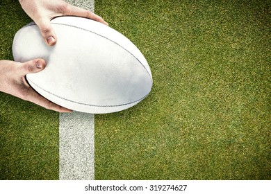 Rugby player catching a rugby ball against pitch with line - Powered by Shutterstock