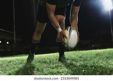 Rugby player dropping the ball to the ground for kicking as it touches the ground.