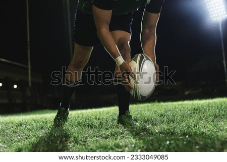 Rugby player dropping the ball to the ground for kicking as it touches the ground.