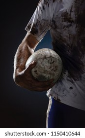 Rugby Player Hands With Ball On Dark Background. Close Up