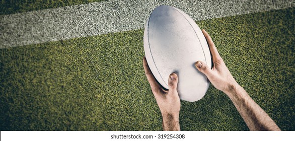 A rugby player posing a rugby ball against pitch with line - Powered by Shutterstock