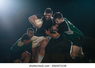 Rugby player in possession of the ball and attempting to advance. Rugby players blocking and tackling opponent player to get the ball. - Powered by Shutterstock