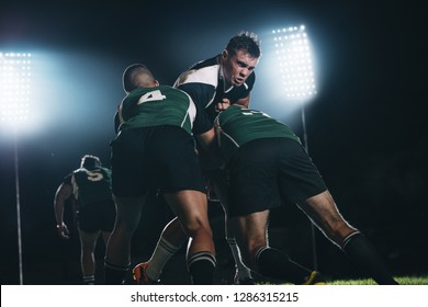 Rugby players fighting for the ball during the night game. Rugby player tackled opponent team players in match. - Powered by Shutterstock