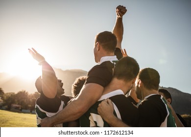 Rugby players lifting the teammate after winning the game. Rugby team celebrating the victory.