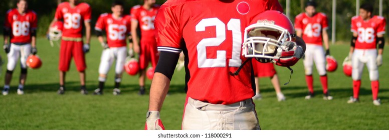 Rugby Team, Banner Background With Rugby Or American Football Team On Green Field In Sunny Day With Copy Space. American Football Team Sport Concept Photo. Sport Background Or Surface With Red Uniform