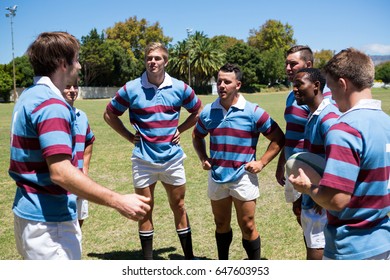 Rugby team discussing while standing at playing field on sunny day  - Powered by Shutterstock