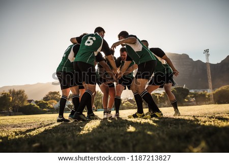 Rugby team putting their hands together after victory. Rugby players cheering and celebrating win.