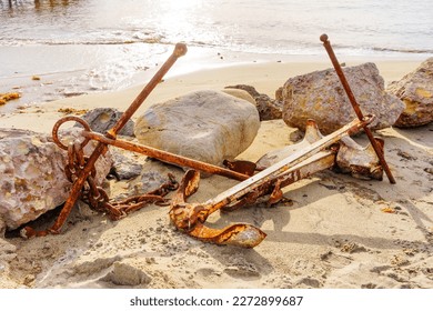 Rugged beauty of old, rusty anchors and chains on a sandy beach. - Powered by Shutterstock