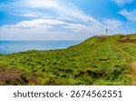 Rugged cliffs below Mull of Galloway Lighthouse, Scotland’s southernmost point, overlook the calm Atlantic Ocean. A peaceful summer scene full of natural beauty
