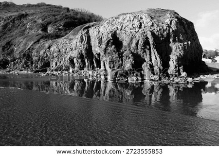 Rugged cliffs with reflections in a pool of water at the Dolwen Point in Pendine, Carmarthenshire, Wales, UK.