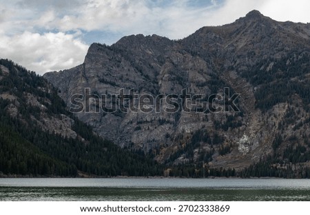 The rugged cliffs and tree lined lower slopes of Prospectors Mountain reflected in the waters of Phelps Lake in Grand Teton National Park
