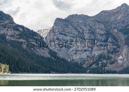 The rugged cliffs and tree lined lower slopes of Prospectors Mountain reflected in the waters of Phelps Lake in Grand Teton National Park 